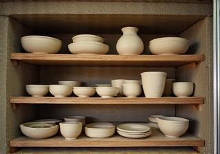 An open ceramic kiln with shelves stacked with dry ceramic pieces ready for the first firing
